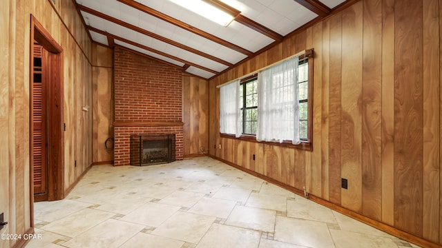 unfurnished living room with beamed ceiling, wood walls, and brick wall