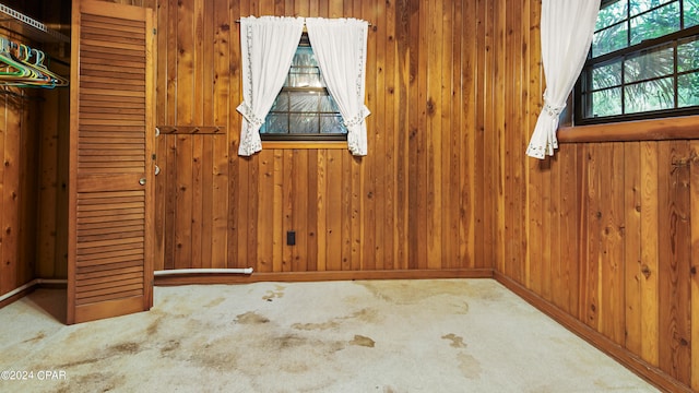 carpeted empty room featuring wooden walls