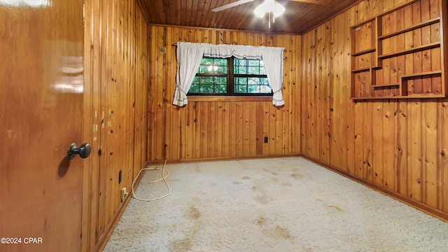 spare room featuring ceiling fan and wooden walls