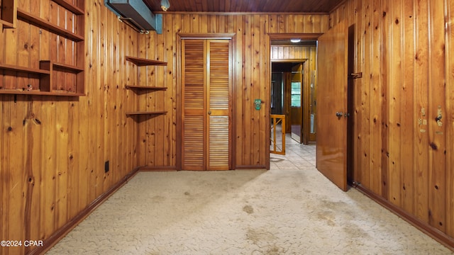 corridor featuring wood walls and light colored carpet