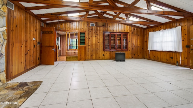 unfurnished living room with vaulted ceiling with beams, light tile patterned flooring, and wood walls