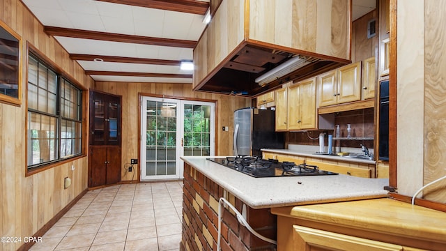 kitchen with black gas stovetop, light brown cabinets, wooden walls, vaulted ceiling with beams, and light tile patterned floors