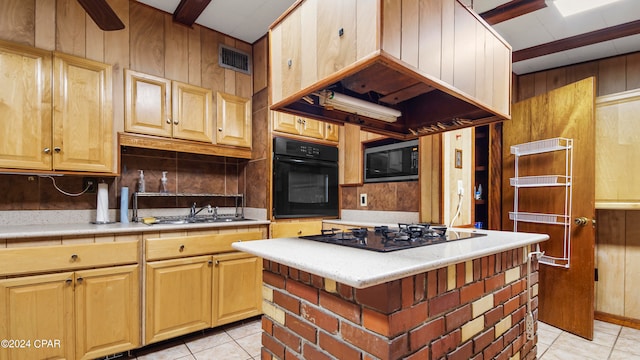 kitchen featuring light tile patterned flooring, a kitchen island, sink, and black appliances