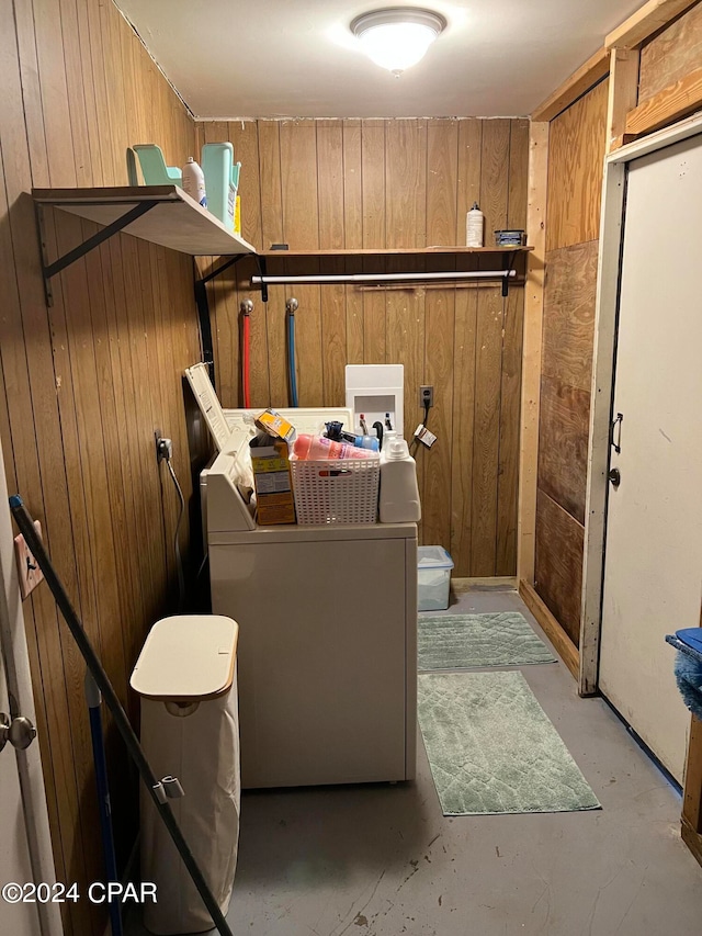 clothes washing area featuring wood walls and washer / dryer