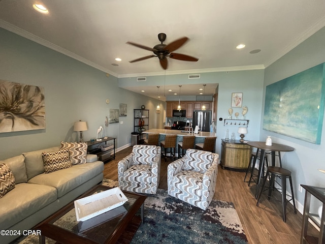 living room featuring baseboards, ornamental molding, visible vents, and light wood-style floors