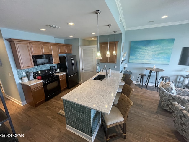 kitchen featuring hanging light fixtures, brown cabinetry, a sink, a peninsula, and black appliances