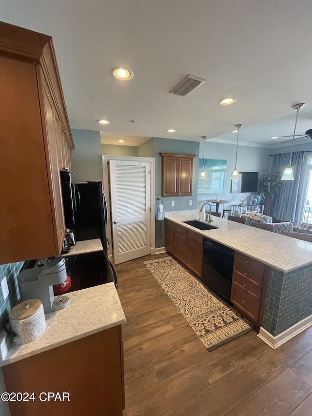 kitchen with decorative light fixtures, visible vents, brown cabinetry, a sink, and black appliances