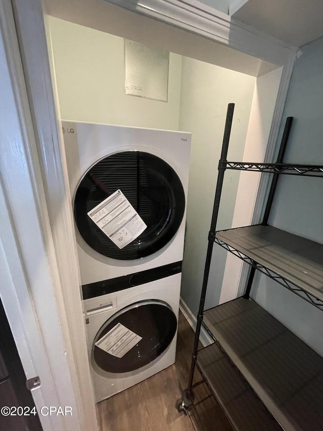 laundry room with wood finished floors, stacked washer and clothes dryer, and laundry area