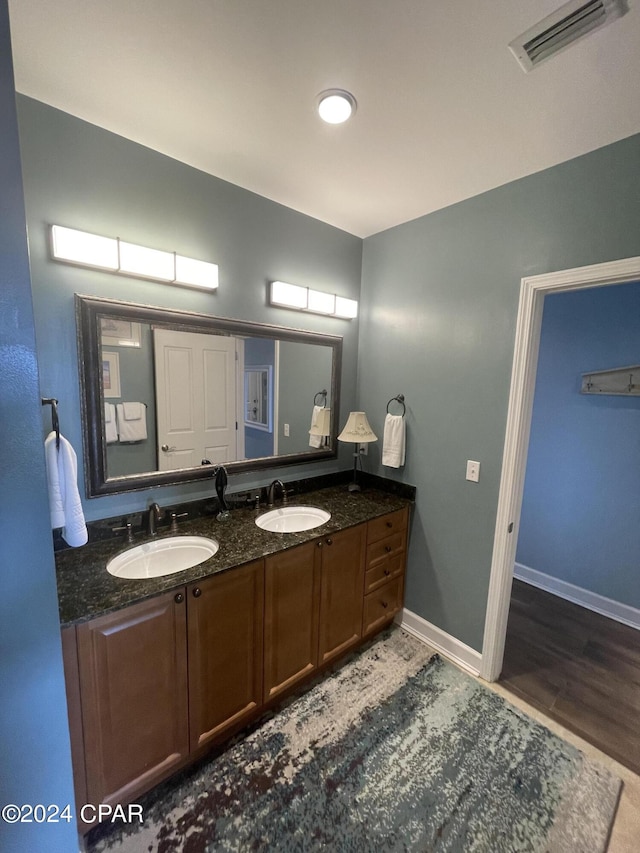 bathroom featuring visible vents, a sink, baseboards, and double vanity