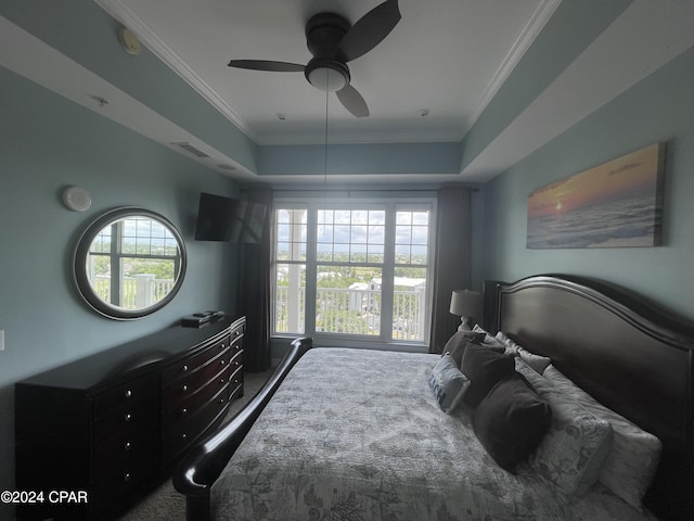 bedroom featuring multiple windows, ornamental molding, and a tray ceiling