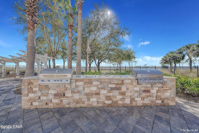 view of patio with a grill, fence, and an outdoor kitchen