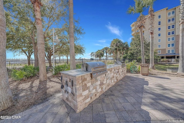 view of patio / terrace featuring grilling area, fence, and an outdoor kitchen