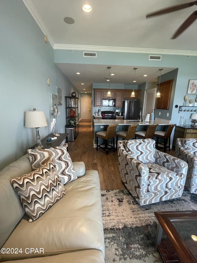 living area featuring visible vents, dark wood-style flooring, and ornamental molding