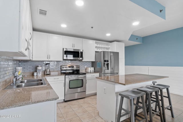 kitchen featuring stainless steel appliances, light tile flooring, sink, and light stone counters