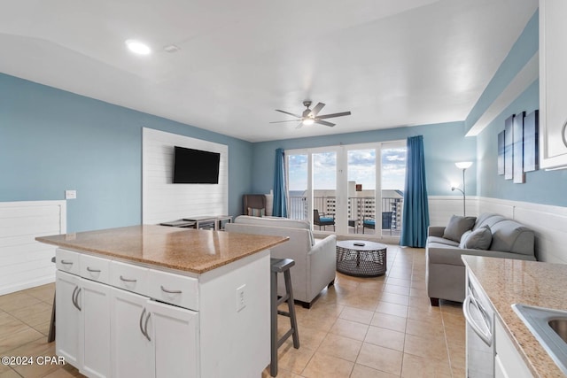 kitchen featuring white cabinetry, light stone counters, ceiling fan, and light tile flooring