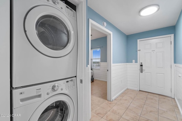 clothes washing area featuring stacked washer / dryer and light tile floors