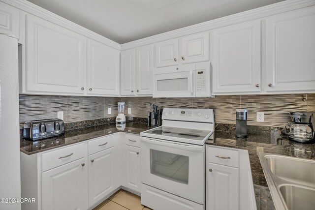 kitchen featuring dishwasher, sink, white cabinets, and dark stone counters