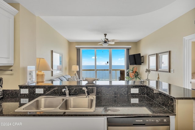 kitchen featuring white cabinets, sink, dishwashing machine, and dark stone counters