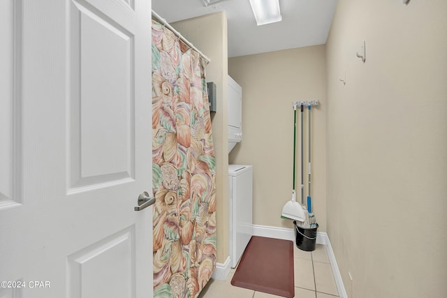 bathroom with stacked washer / dryer and tile patterned floors