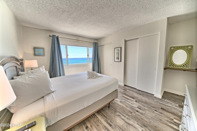 bedroom featuring hardwood / wood-style flooring, two closets, a textured ceiling, and a water view