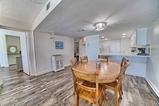 dining space featuring a textured ceiling, sink, and dark wood-type flooring