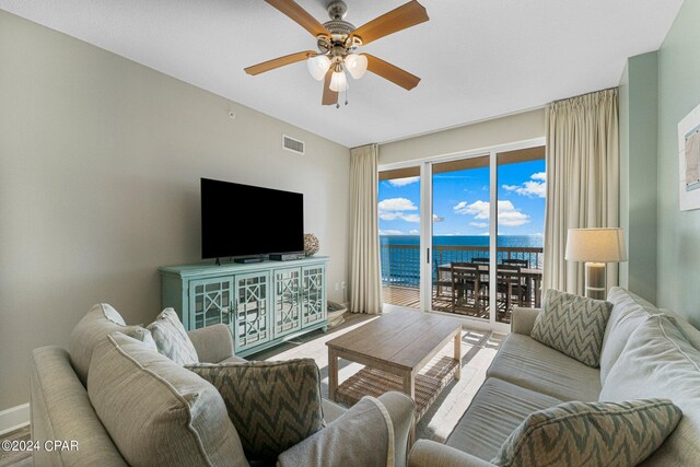 living room with ceiling fan and a water view