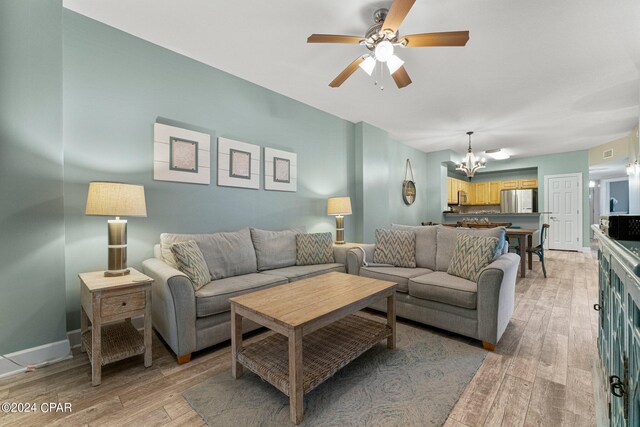 living room featuring ceiling fan with notable chandelier and wood-type flooring