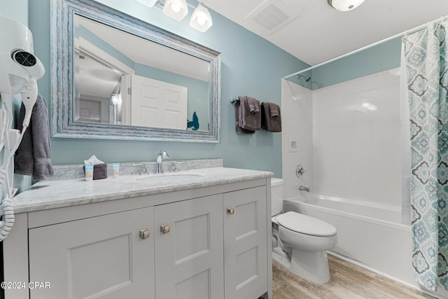 full bathroom featuring hardwood / wood-style flooring, shower / bath combo, vanity, and toilet