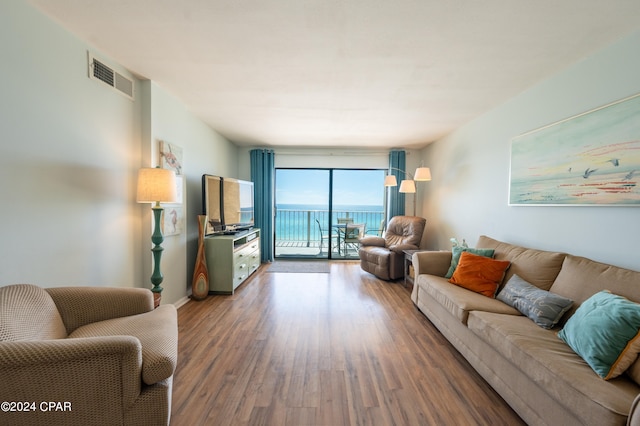 living room featuring floor to ceiling windows, a water view, and dark hardwood / wood-style floors