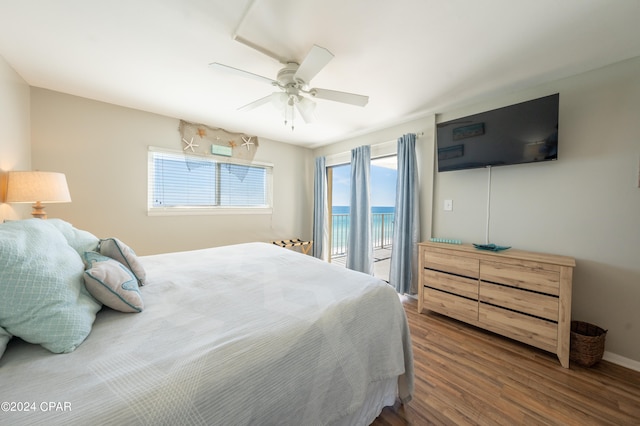 bedroom featuring a water view, ceiling fan, hardwood / wood-style flooring, and access to exterior