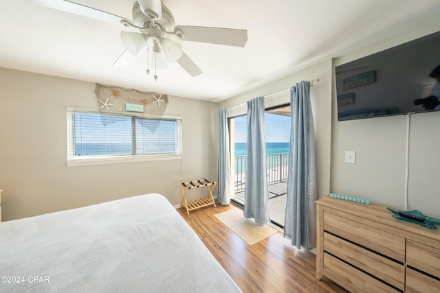 bedroom with wood-type flooring, ceiling fan, access to exterior, and a water view