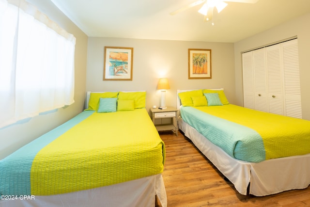 bedroom featuring wood-type flooring, ceiling fan, and a closet