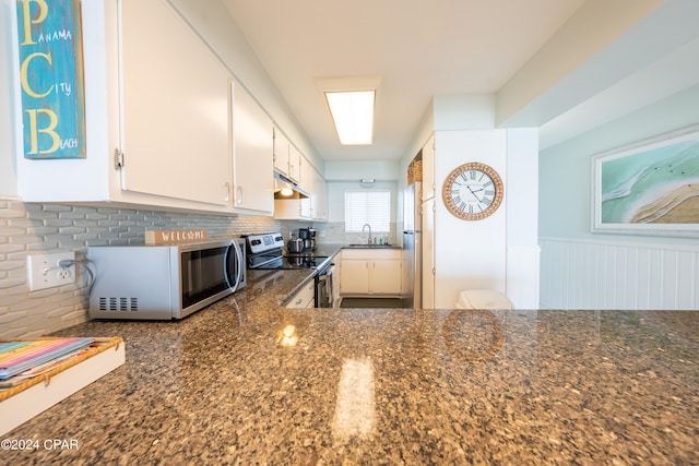 kitchen featuring backsplash, stainless steel appliances, dark stone counters, white cabinets, and sink