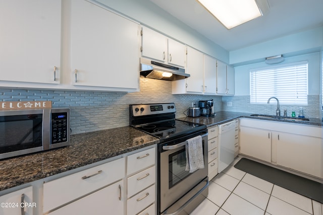 kitchen with appliances with stainless steel finishes, light tile floors, sink, backsplash, and white cabinetry