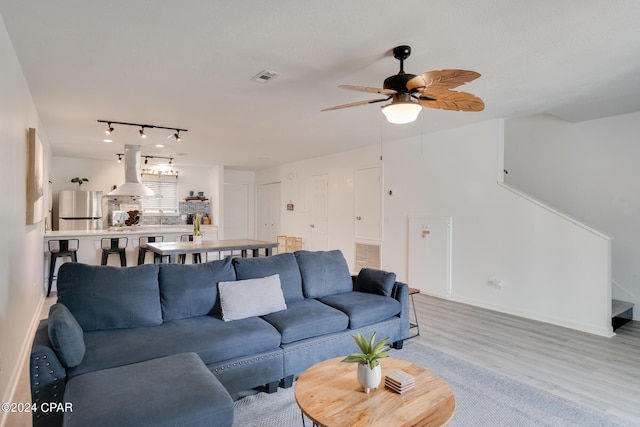 living room with ceiling fan, track lighting, and light wood-type flooring