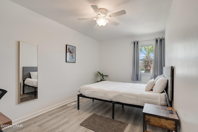 bedroom featuring a textured ceiling, light wood-type flooring, and ceiling fan