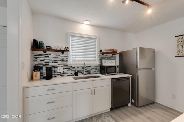 kitchen with sink, stainless steel appliances, tasteful backsplash, light hardwood / wood-style floors, and white cabinets