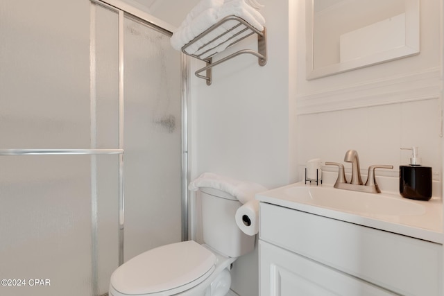 bathroom featuring a shower with door, vanity, and toilet