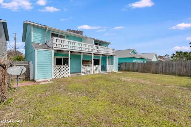 rear view of house featuring a lawn and a balcony