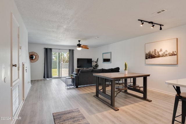 dining space featuring ceiling fan, light wood-type flooring, and a textured ceiling