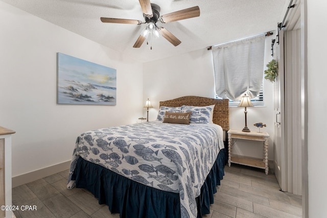 bedroom with a textured ceiling, ceiling fan, and light wood-type flooring