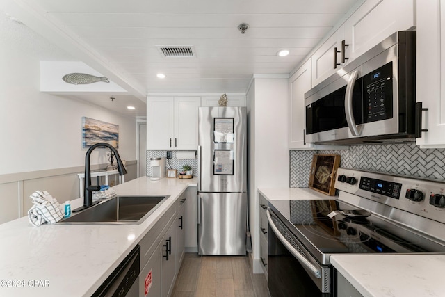 kitchen featuring tasteful backsplash, stainless steel appliances, white cabinetry, and light wood-type flooring