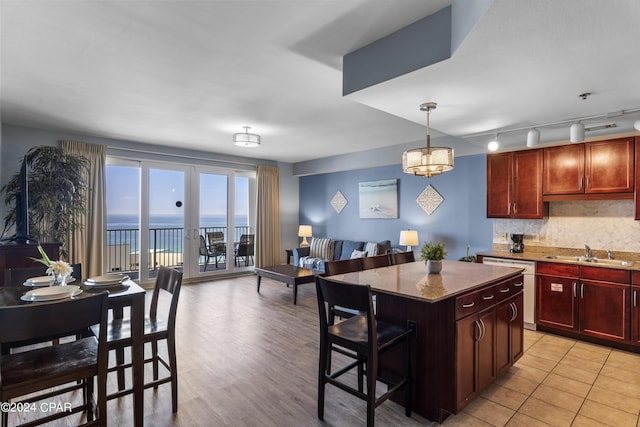 kitchen with sink, a breakfast bar, a water view, light stone counters, and a kitchen island