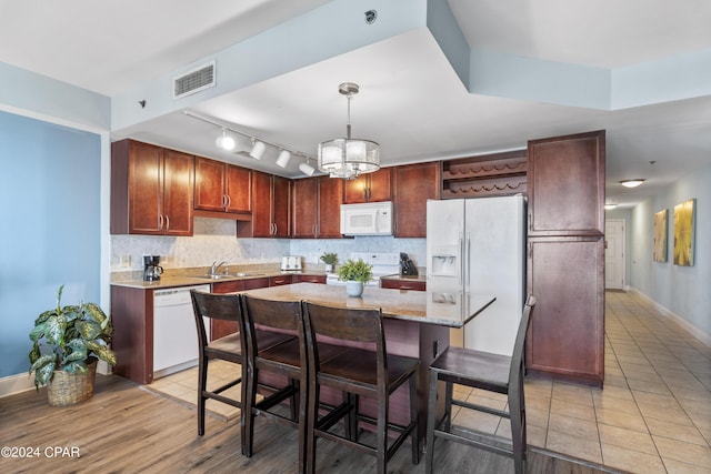 kitchen with decorative light fixtures, sink, backsplash, a center island, and white appliances