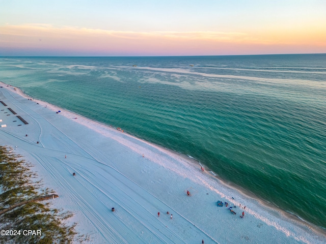 aerial view at dusk with a water view and a view of the beach