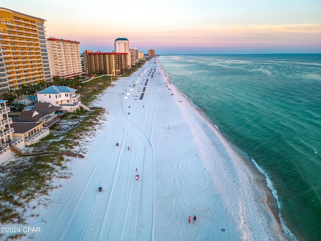 aerial view at dusk with a water view and a view of the beach