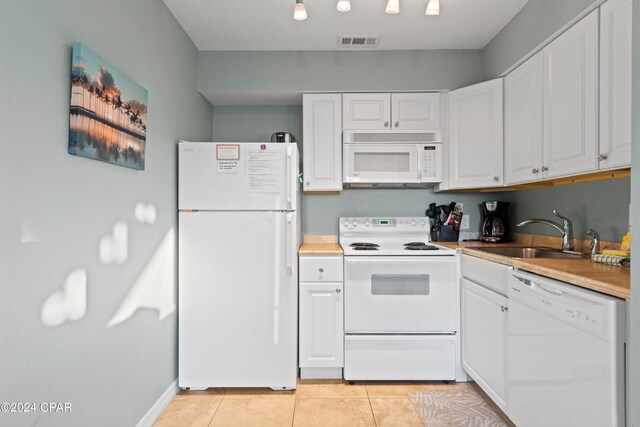 kitchen with white appliances, white cabinetry, light tile floors, and sink