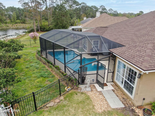 view of swimming pool featuring glass enclosure, a water view, and a patio area