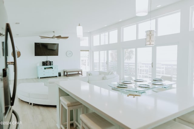 kitchen with a kitchen breakfast bar, light hardwood / wood-style floors, hanging light fixtures, and a high ceiling