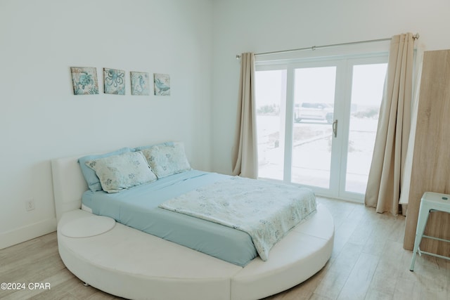 bedroom with access to exterior, light wood-style flooring, multiple windows, and baseboards